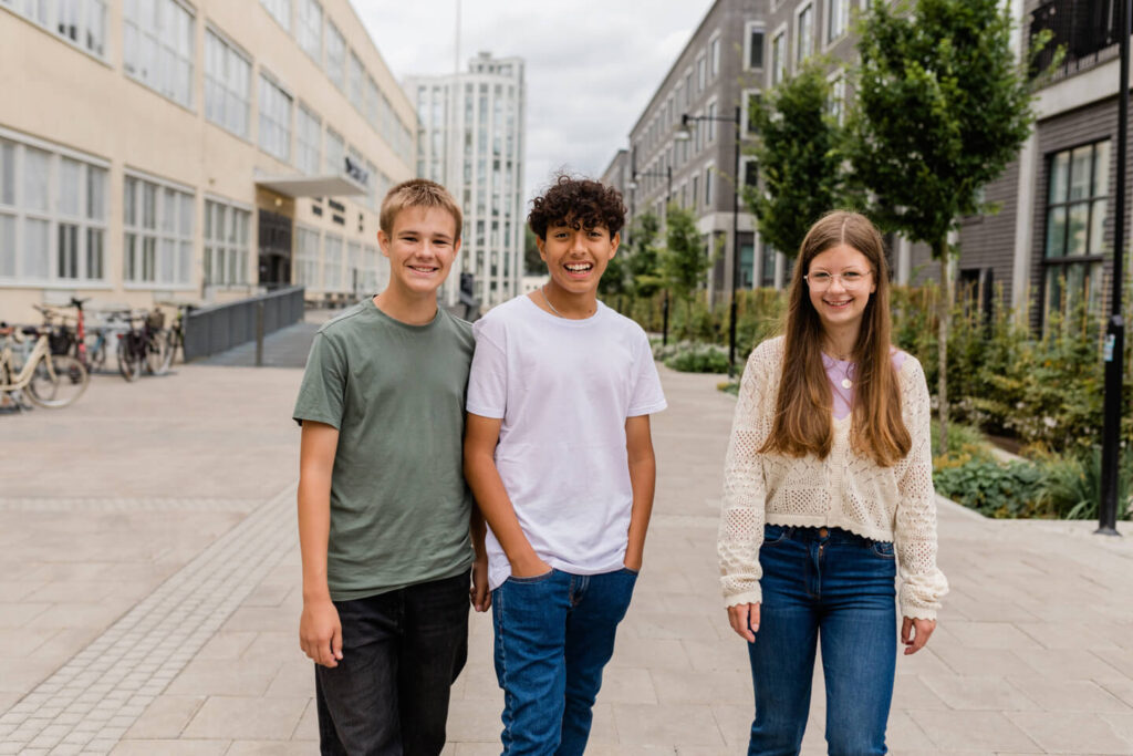 Three young people walking smiling in a schoolyard