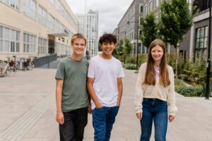 Tre ungdomar promenerar leende på en skolgård