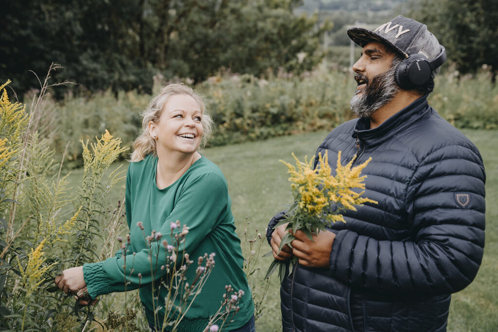 A man and a woman are picking flowers in a meadow.
